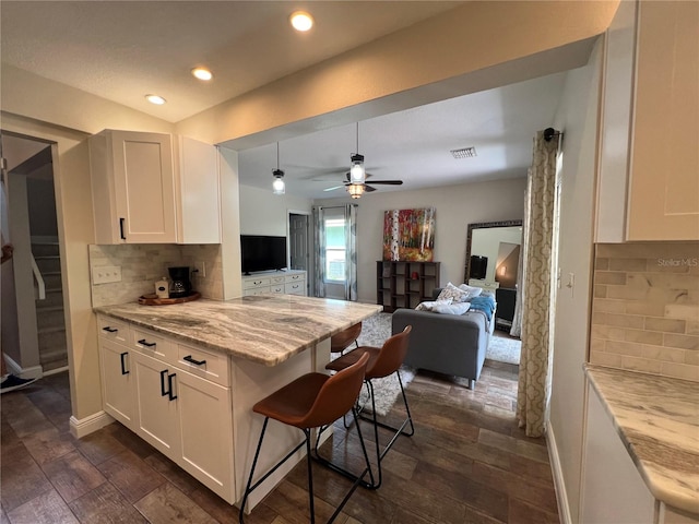 kitchen with light stone countertops, dark hardwood / wood-style flooring, tasteful backsplash, ceiling fan, and white cabinets