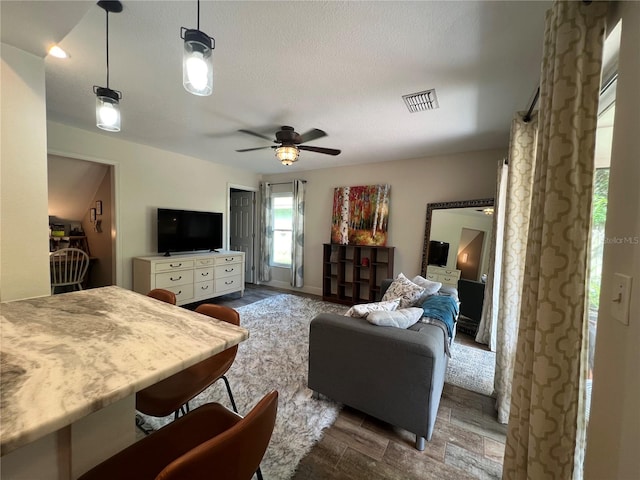 living room featuring a textured ceiling, dark hardwood / wood-style floors, and ceiling fan