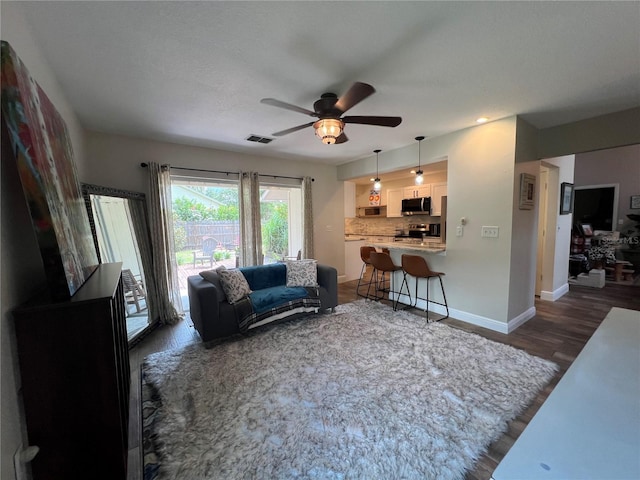 living room with ceiling fan and dark wood-type flooring