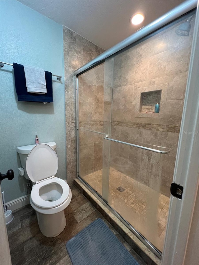 bathroom with toilet, an enclosed shower, and hardwood / wood-style flooring