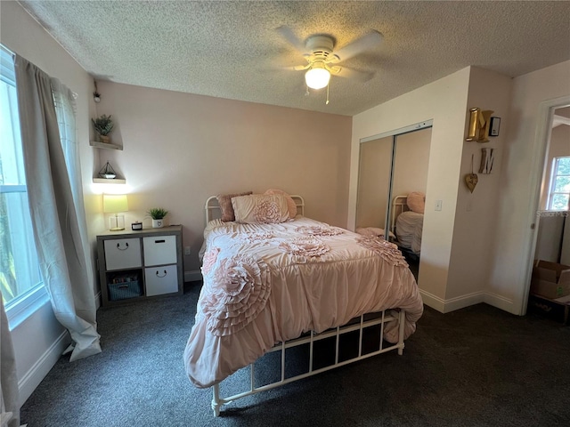 bedroom with dark colored carpet, a textured ceiling, a closet, and ceiling fan