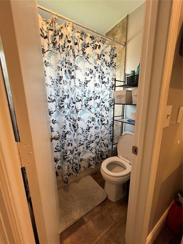 bathroom featuring walk in shower, hardwood / wood-style floors, and toilet