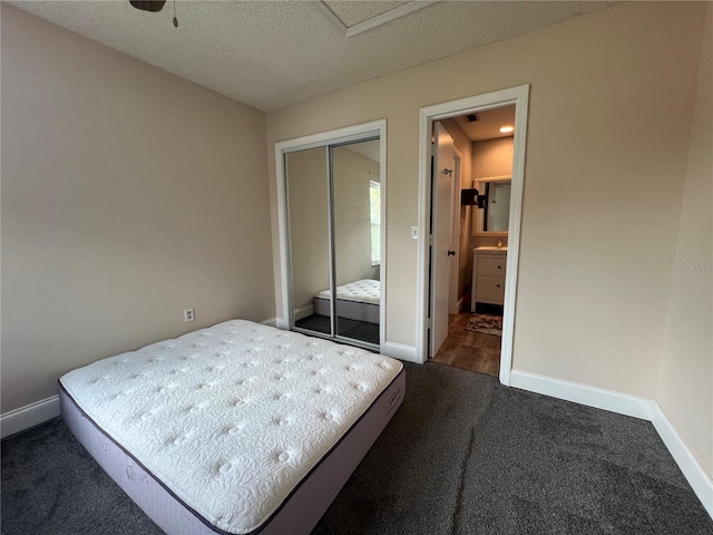 unfurnished bedroom featuring ceiling fan, a closet, a textured ceiling, and dark colored carpet