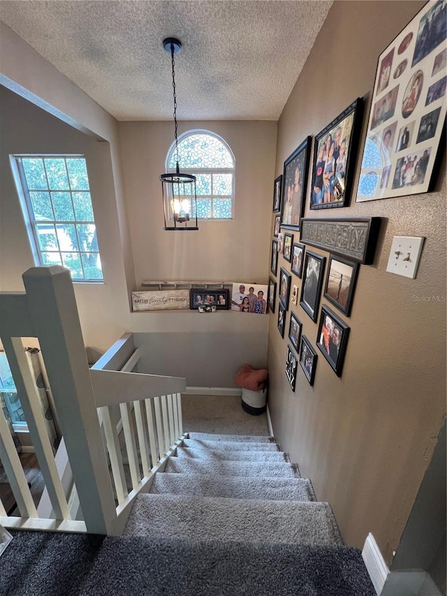 737 Butternut Pl, Lakeland, FL 33813 - staircase featuring carpet flooring, a textured ceiling, and a chandelier