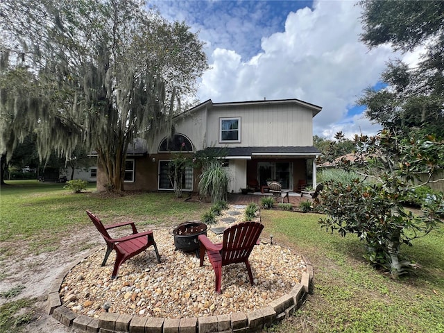 rear view of property with a patio, an outdoor fire pit, and a lawn