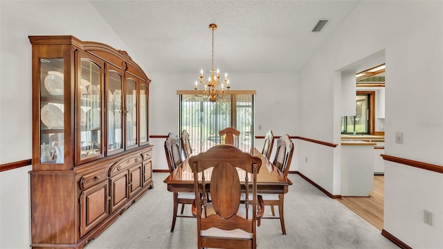 dining space featuring a textured ceiling, light hardwood / wood-style flooring, lofted ceiling, and an inviting chandelier