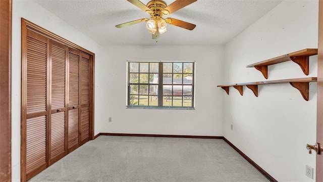 unfurnished bedroom with carpet, a textured ceiling, a closet, and ceiling fan