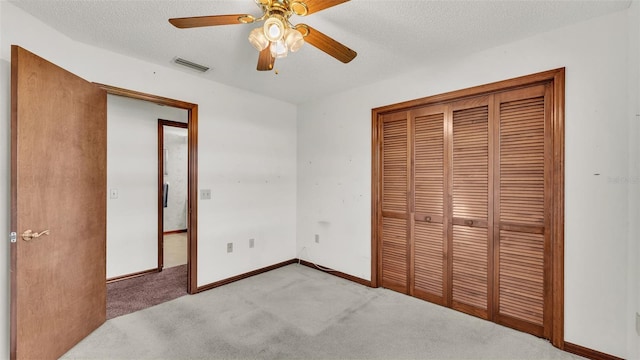 unfurnished bedroom featuring light carpet, a textured ceiling, a closet, and ceiling fan