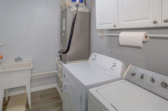 washroom featuring washing machine and dryer, cabinets, and light hardwood / wood-style floors