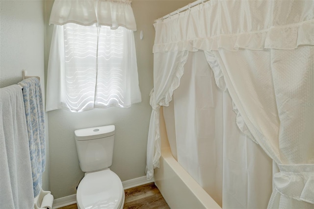 bathroom with toilet, wood-type flooring, and shower / bath combo