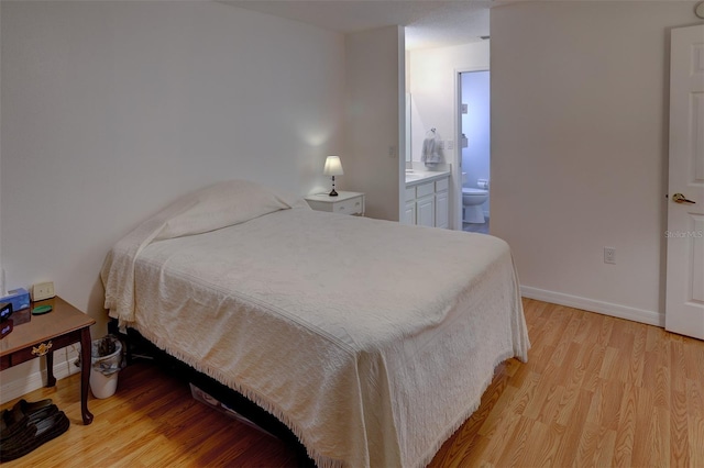 bedroom featuring light wood-type flooring and connected bathroom