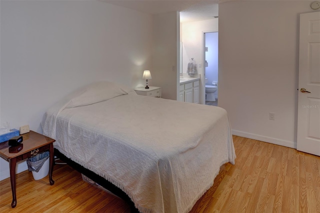 bedroom with ensuite bath and light hardwood / wood-style flooring