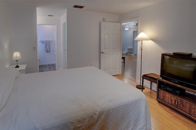 bedroom featuring connected bathroom and light hardwood / wood-style flooring