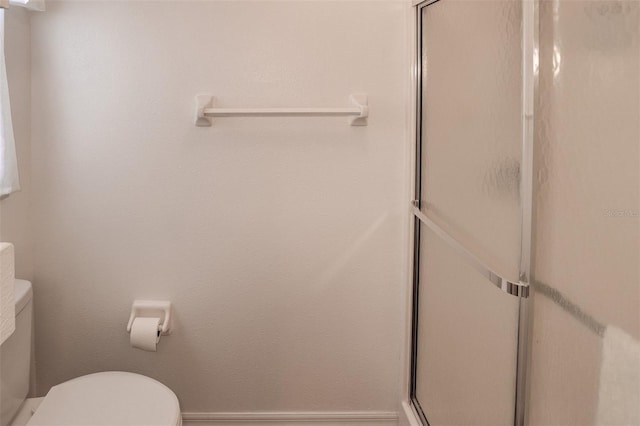 bathroom with toilet and a shower with door