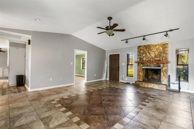 unfurnished living room with a wealth of natural light, a fireplace, track lighting, and vaulted ceiling