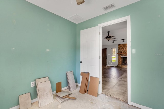 unfurnished room with a stone fireplace and ceiling fan