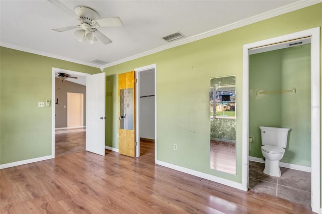 unfurnished bedroom featuring hardwood / wood-style flooring, ceiling fan, ornamental molding, connected bathroom, and a closet