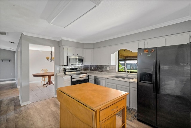 kitchen with appliances with stainless steel finishes, crown molding, sink, white cabinets, and light hardwood / wood-style floors