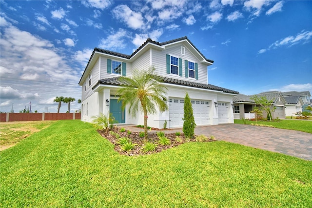 view of front of property featuring an attached garage, fence, decorative driveway, and a front lawn