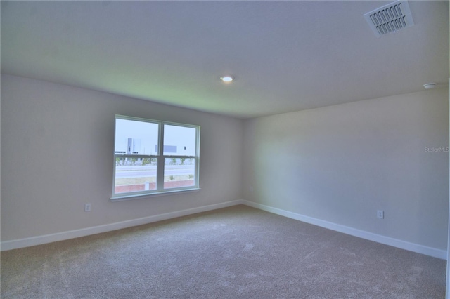 spare room with visible vents, baseboards, and carpet