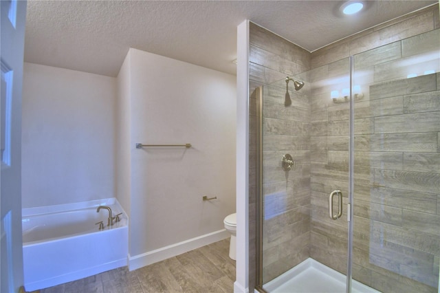 full bath with a stall shower, a textured ceiling, toilet, a bath, and wood finished floors