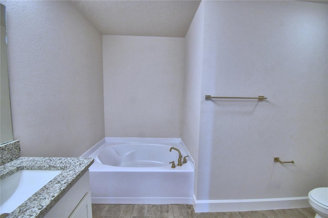 bathroom with toilet, a bath, vanity, and wood finished floors