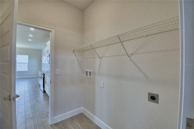 laundry area featuring baseboards, electric dryer hookup, washer hookup, light wood-style floors, and laundry area