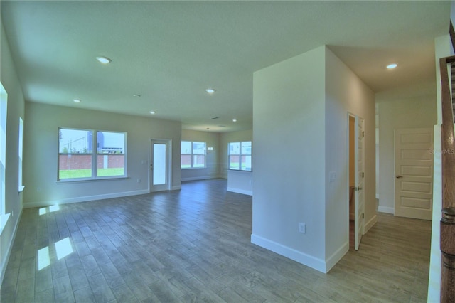 unfurnished living room with baseboards, recessed lighting, and wood finished floors