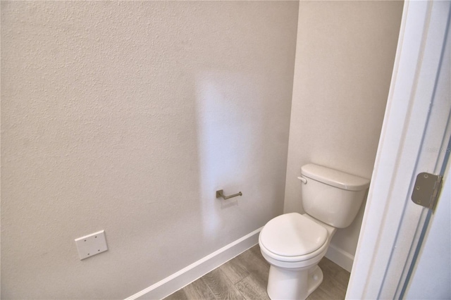 bathroom with toilet, wood finished floors, and baseboards