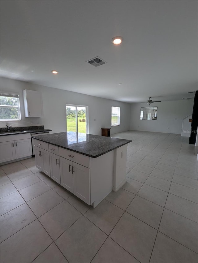 kitchen featuring ceiling fan, sink, dark stone countertops, white cabinets, and a kitchen island