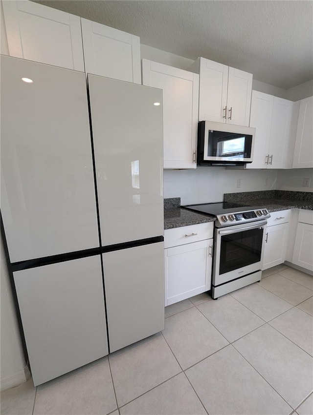 kitchen featuring white cabinets, light tile patterned floors, range with electric cooktop, and a textured ceiling