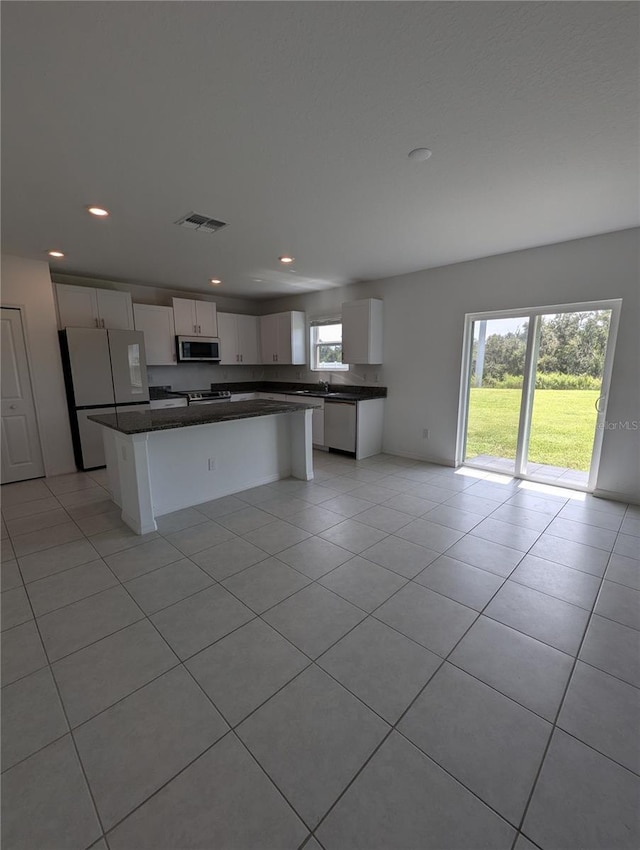 kitchen featuring white cabinets, a center island, light tile patterned floors, and stainless steel appliances