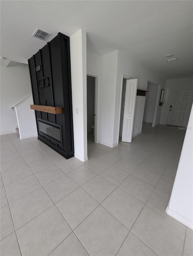 unfurnished living room with light tile patterned flooring and a textured ceiling