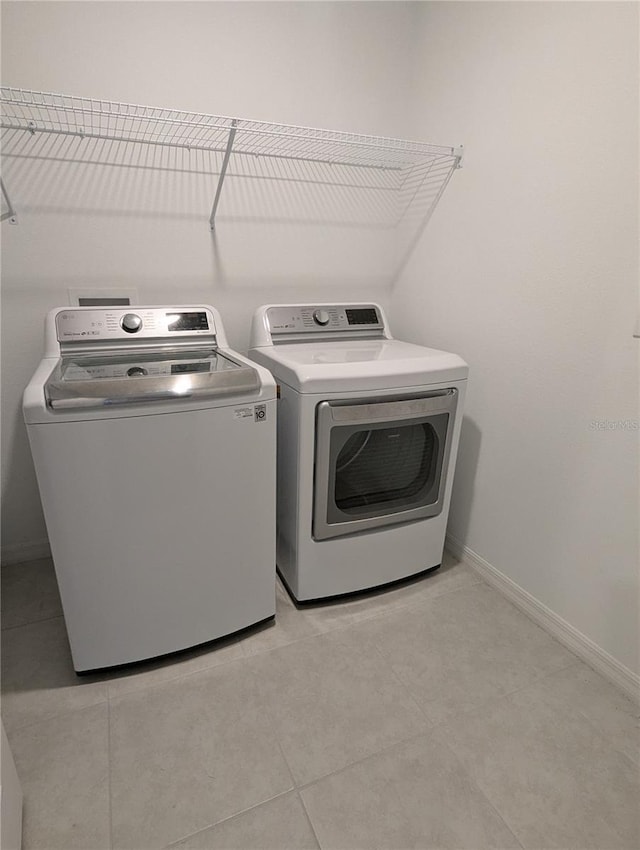 laundry area with washing machine and dryer and light tile patterned floors