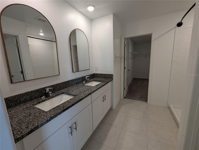 bathroom featuring tile patterned floors, a shower, and vanity