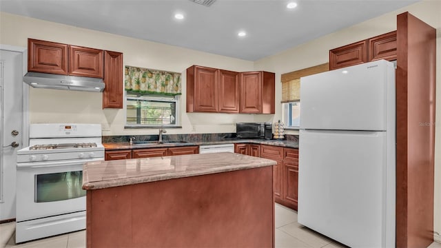 kitchen with a center island, light stone countertops, white appliances, and sink