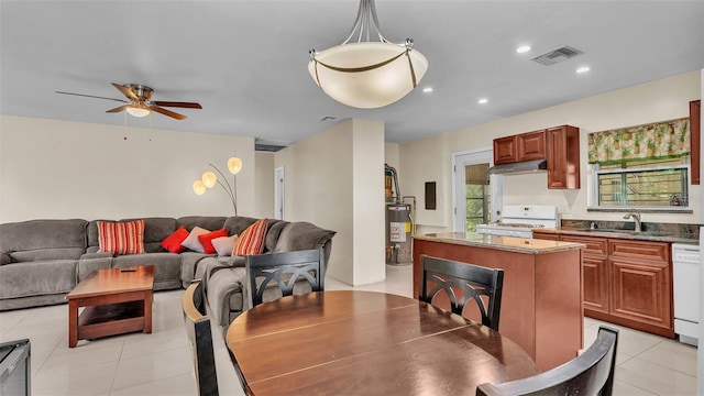 tiled dining space featuring ceiling fan, gas water heater, and sink