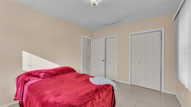 tiled bedroom featuring two closets