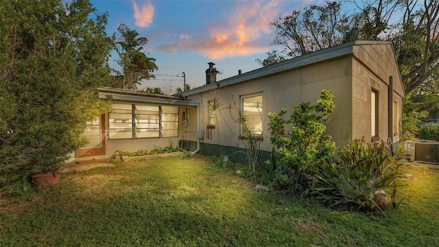 back house at dusk with central AC unit and a yard