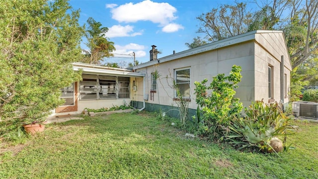 rear view of house with central air condition unit and a lawn