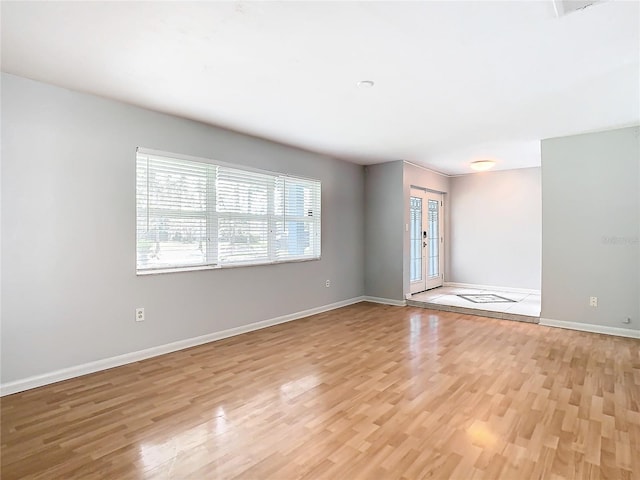 spare room featuring french doors and light hardwood / wood-style flooring