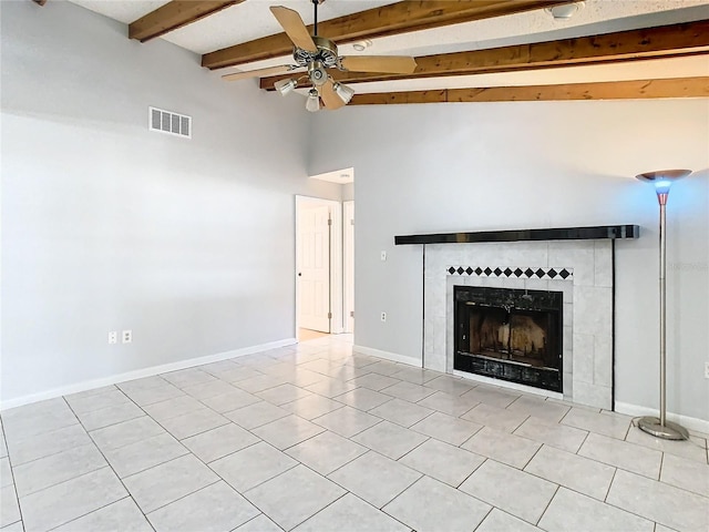 unfurnished living room with light tile patterned floors, vaulted ceiling with beams, ceiling fan, and a tiled fireplace