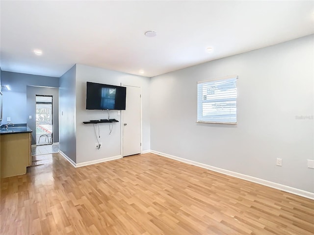 unfurnished living room with sink and light hardwood / wood-style floors