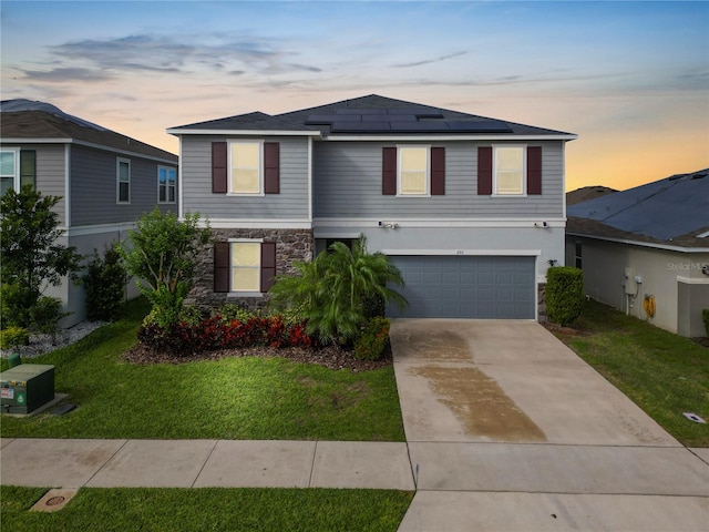 view of front of house featuring solar panels, a garage, and a lawn