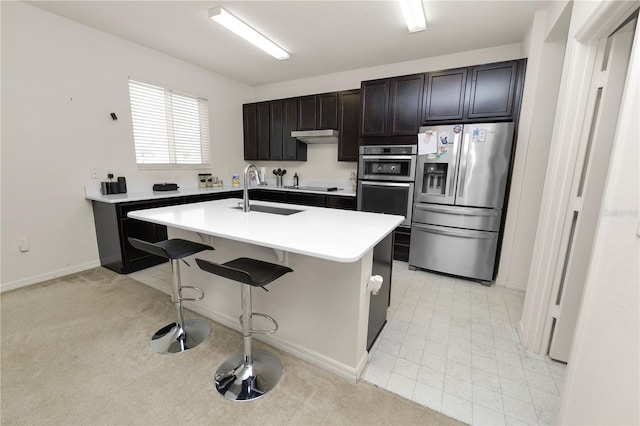 kitchen featuring a center island with sink, sink, a kitchen bar, and stainless steel appliances