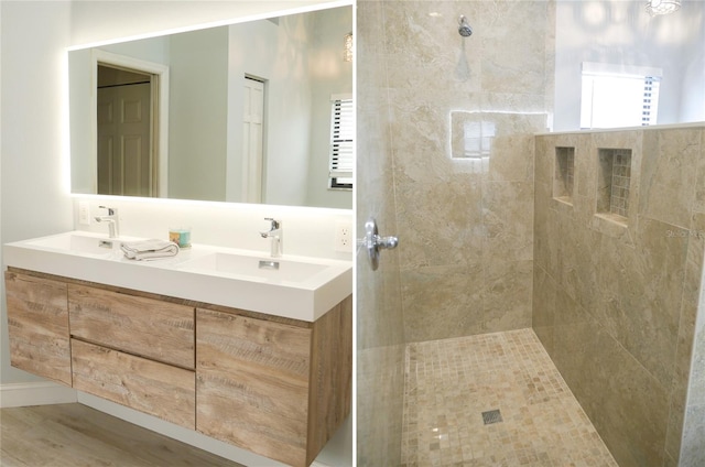 bathroom featuring hardwood / wood-style floors, vanity, and a tile shower