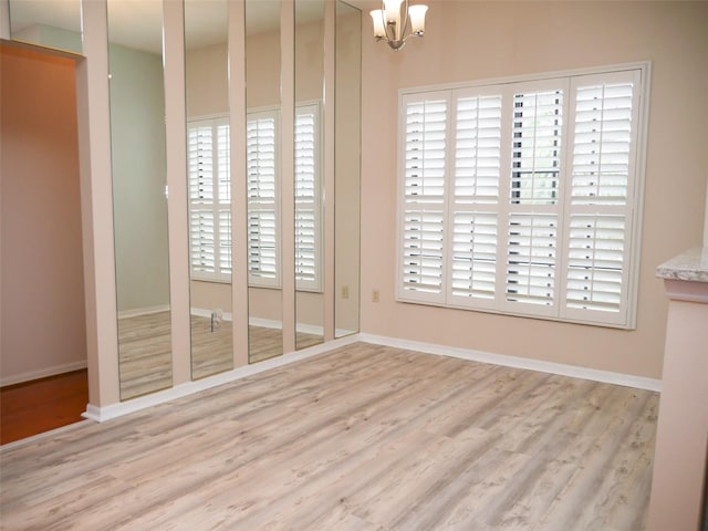 unfurnished dining area featuring a notable chandelier and light wood-type flooring