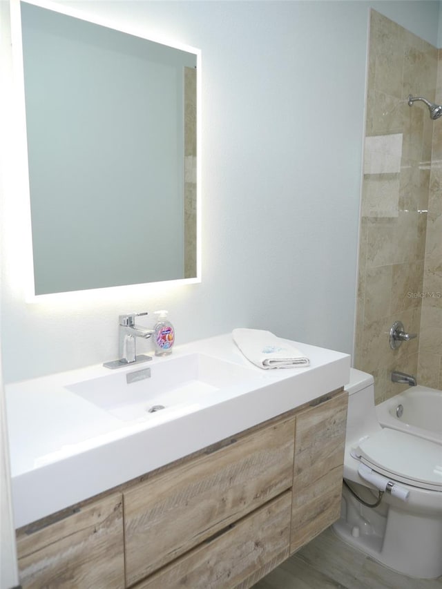 full bathroom with vanity, wood-type flooring, tiled shower / bath combo, and toilet