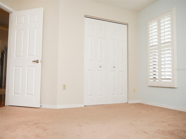 unfurnished bedroom with light carpet and a closet