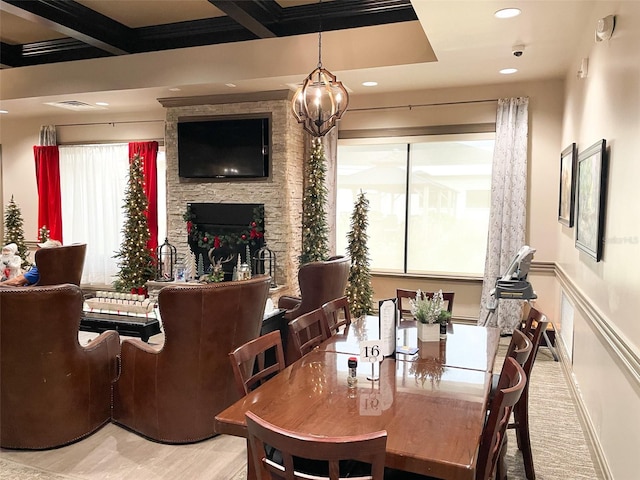 dining area with coffered ceiling, beamed ceiling, a notable chandelier, a fireplace, and light hardwood / wood-style floors